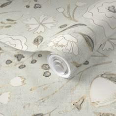 the wallpaper is white with gold and silver designs on it's surface, as well as a roll of tape