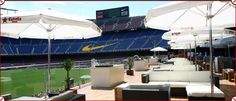 an outdoor seating area with white umbrellas and seats on the sidelines at a stadium