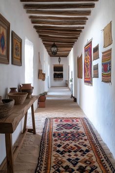 a long hallway with many pictures on the wall and rugs hanging from the ceiling