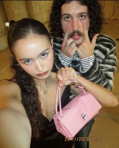 a man holding a pink purse next to a woman with her finger on her lips