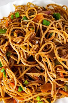 a plate full of noodles with carrots and green onions