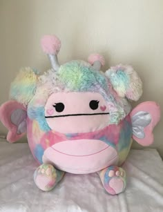 a pink and blue stuffed animal sitting on top of a bed