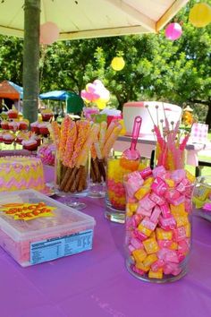 a table topped with lots of candy covered in pink, yellow and orange candies