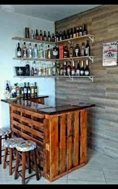 a wooden bar with stools and shelves filled with bottles on the wall behind it