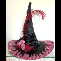 a witches hat with pink and black feathers