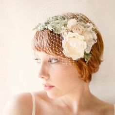 a woman wearing a veil and flower headpiece with flowers on it's side