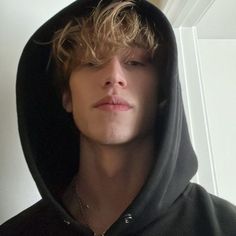 a young man with blonde hair wearing a black hoodie and looking at the camera