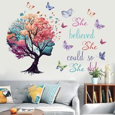 a living room with a white couch and wall decal that says she believed she could so she did