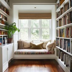 a window seat in the corner of a room with bookshelves full of books