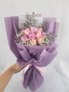 a hand holding a bouquet of pink roses and baby's breath