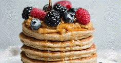 a stack of pancakes topped with berries and syrup