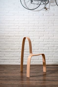 a wooden chair sitting on top of a hard wood floor next to a white brick wall