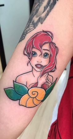 the little mermaid tattoo is on someone's arm and it looks like she has an orange flower in her hand