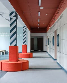 an empty hallway with orange chairs and white walls