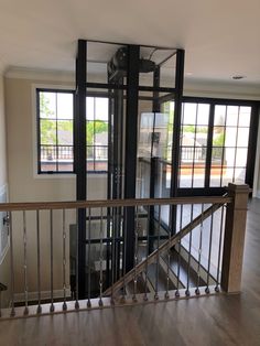 an empty living room with wood floors and black glass doors on the second story railing