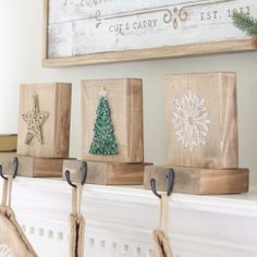 three wooden blocks with christmas decorations on them hanging from the mantel in front of a fireplace