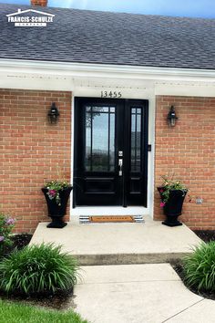 a black front door with two planters on it