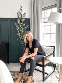 a woman sitting in a chair next to a bed with a plant on top of it