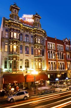 the hotel is lit up at night with cars passing by