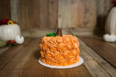 an orange frosted cake sitting on top of a wooden table