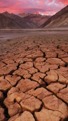 the desert is dry and has little grass growing on it, with mountains in the background