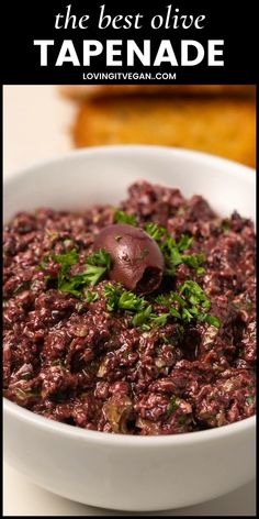 the best olive tapenad recipe is in a white bowl with parsley on top