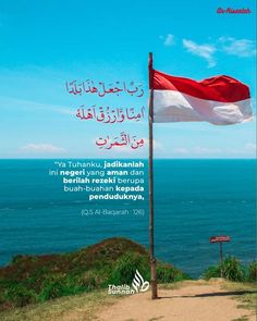 a flag flying on top of a hill next to the ocean with an arabic quote