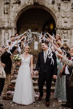 a bride and groom are walking down the steps with their guests holding streamers in front of them