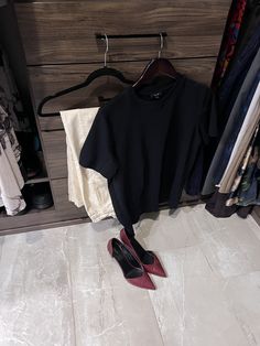 a pair of red shoes sitting on the floor next to a black t - shirt