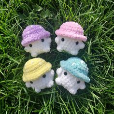 four small crocheted hats sitting in the grass