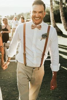 a man and woman holding hands while walking down the aisle at an outdoor wedding ceremony