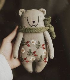 a hand holding a stuffed animal with flowers on it