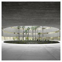 the entrance to an office building with palm trees in front of it and concrete walls