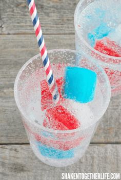 two glasses filled with red, white and blue jellopops sitting on top of a wooden table