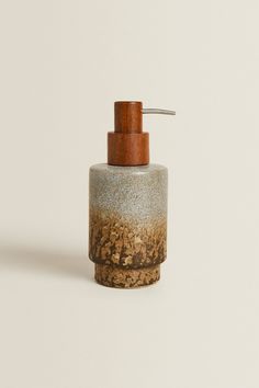 a soap dispenser made out of concrete with a wooden top on a white background