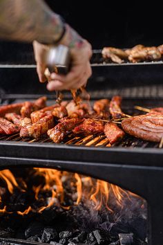 someone is grilling meat and sausages on the grill