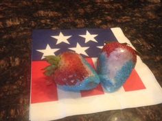 two strawberries sitting on top of an american flag napkin