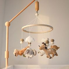 a baby crib mobile with stuffed animals hanging from it's sides, in a white room