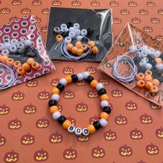 three halloween bracelets are shown in plastic bags and on the table is an assortment of beads