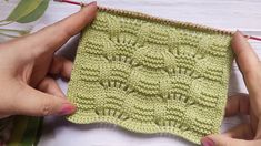 two hands holding up a green knitted square