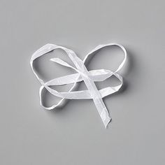 a piece of white ribbon on a gray surface with one knot tied in the middle