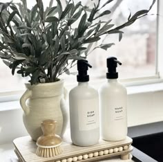 two bottles are sitting on a table next to a vase with a plant in it