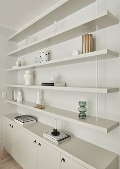 the shelves are lined with books, vases and other decorative items in white colors