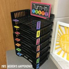 a stack of black plastic bins sitting on top of a table next to a wall