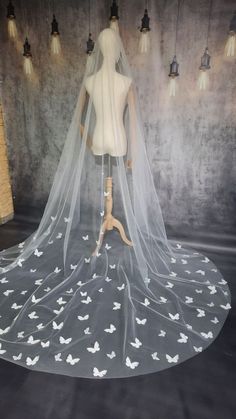 a wedding veil with white butterflies on it is displayed in front of a mannequin