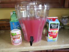 a blender filled with pink liquid sitting on top of a counter next to bottles of juice