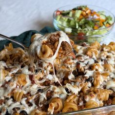 a spoonful of pasta with meat and cheese being lifted from a casserole dish