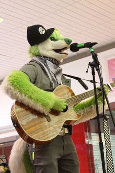 a person in a costume playing a guitar and singing into a microphone while wearing a hat