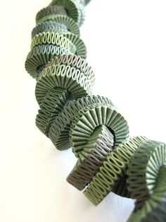 several pieces of green and white paper are arranged in the shape of spirals on a white surface