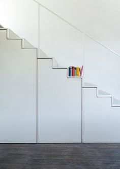 there is a book shelf on the bottom of this stair case that has books in it